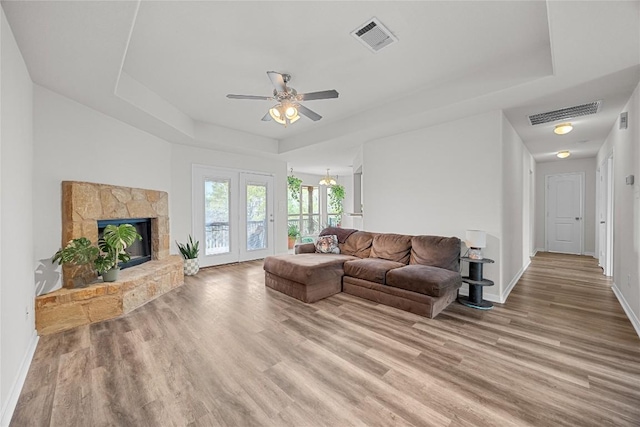 living room featuring visible vents, a ceiling fan, a raised ceiling, and wood finished floors
