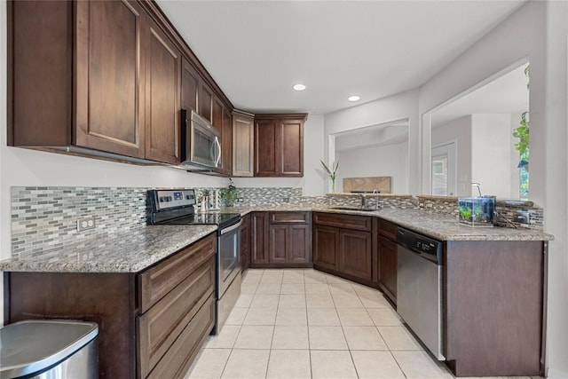 kitchen with appliances with stainless steel finishes, a sink, light tile patterned floors, a peninsula, and recessed lighting