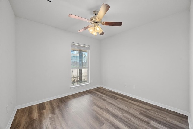 empty room with baseboards, ceiling fan, and dark wood-type flooring