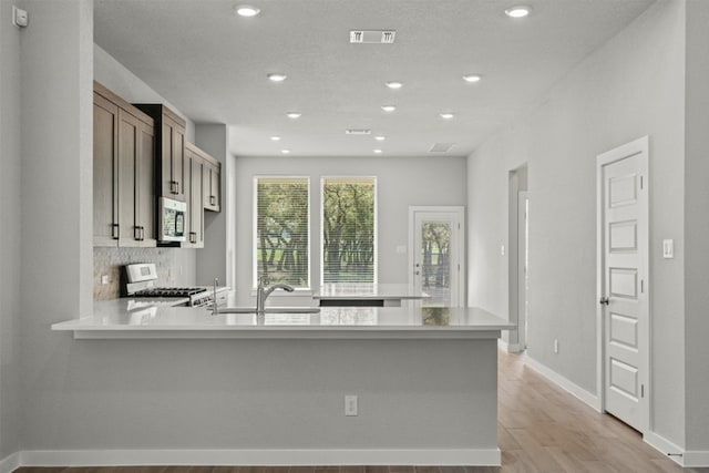 2705 Sage Ranch Dr Unit 25, Leander, TX 78641 - kitchen featuring stove, stainless steel microwave, light countertops, a peninsula, and a sink