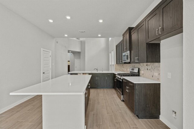 2705 Sage Ranch Dr Unit 25, Leander, TX 78641 - kitchen with stainless steel appliances, light wood-style flooring, a peninsula, dark brown cabinets, and recessed lighting