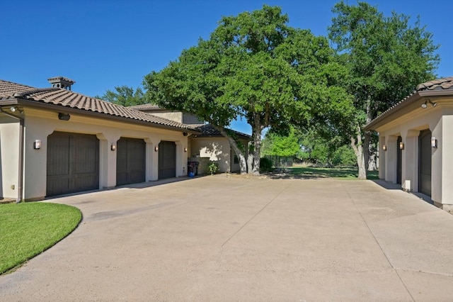 view of home's exterior featuring an attached garage, stucco siding, a tile roof, and concrete driveway