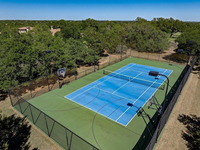 view of sport court featuring a view of trees and fence