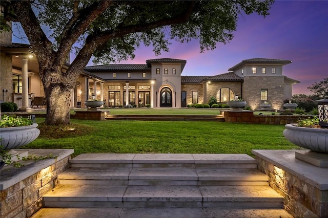 511 County Road 262, Georgetown, TX 78633 - back of property at dusk featuring a tile roof, a lawn, stone siding, and stucco siding