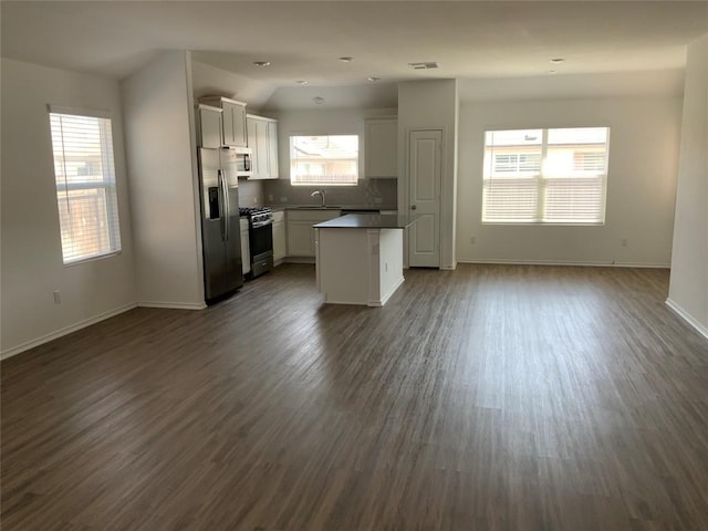 kitchen featuring open floor plan, stainless steel fridge, plenty of natural light, dark wood-type flooring, and gas stove