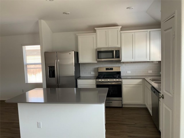 kitchen featuring dark wood-style flooring, white cabinetry, backsplash, vaulted ceiling, and stainless steel appliances