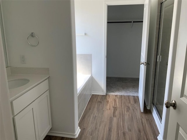 bathroom with vanity, a walk in closet, a stall shower, and wood finished floors