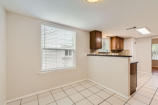 4318 Clarno Dr, Austin, TX 78749 - kitchen with dark countertops, backsplash, light tile patterned floors, baseboards, and a textured ceiling