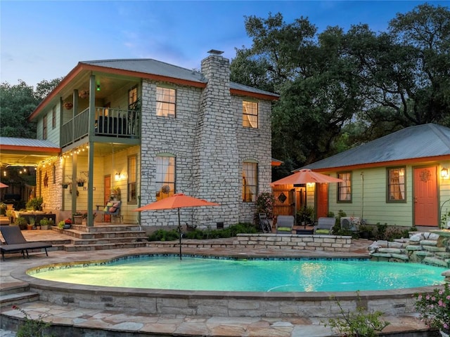 6407 Poncha Pass, Austin, TX 78749 - rear view of property featuring a balcony, an outdoor pool, a chimney, and a patio area