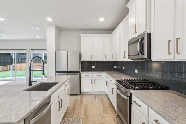 kitchen with a sink, white cabinets, stainless steel appliances, and visible vents