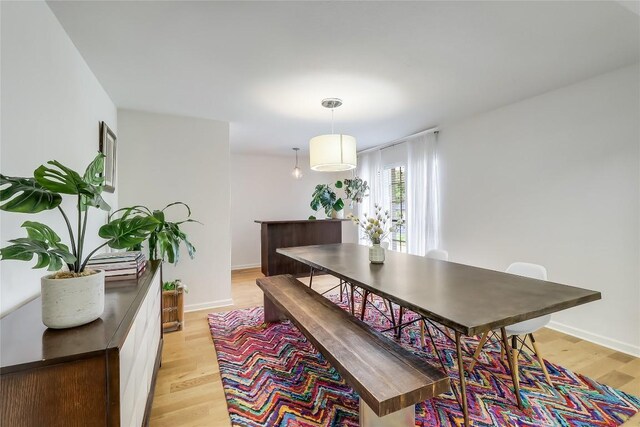 dining space featuring light wood-type flooring and baseboards