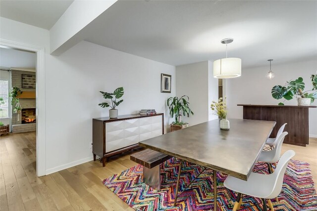 dining room with light wood-style floors, baseboards, and a fireplace