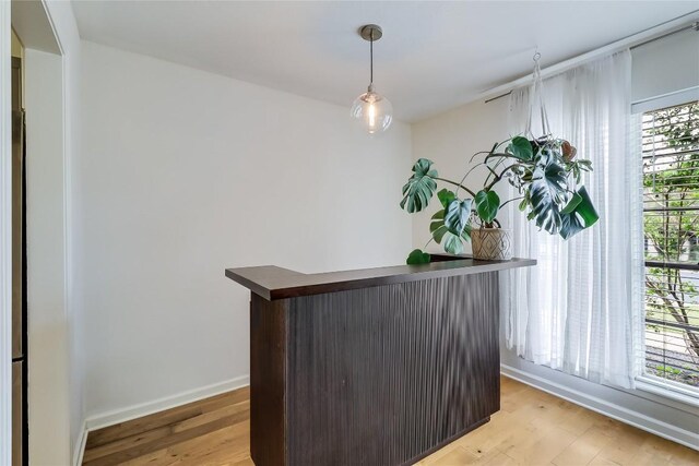 interior space with light wood-style floors, baseboards, a dry bar, and a healthy amount of sunlight