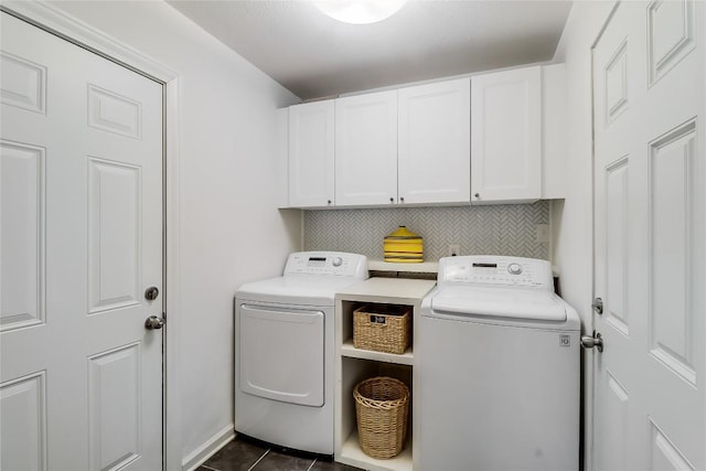 clothes washing area with dark tile patterned flooring, cabinet space, and washing machine and clothes dryer