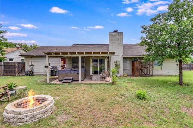 back of house featuring a fire pit, fence, a patio, a chimney, and a hot tub
