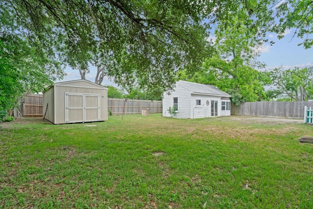 view of yard with an outdoor structure, a fenced backyard, and a storage shed