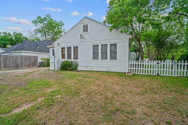 rear view of house featuring a lawn and fence
