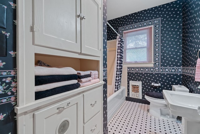 bathroom featuring heating unit, toilet, wallpapered walls, and shower / tub combo