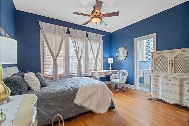 bedroom with light wood-style floors, baseboards, ceiling fan, and ensuite bath