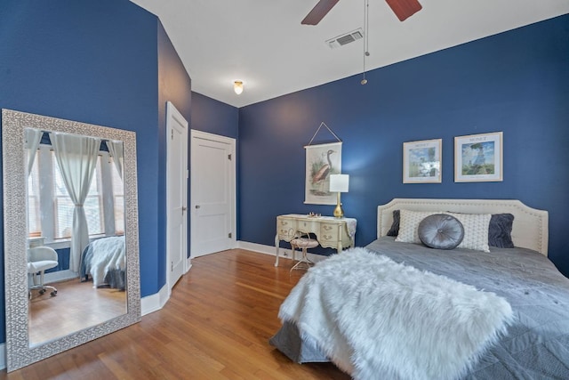 bedroom featuring visible vents, baseboards, ceiling fan, and wood finished floors