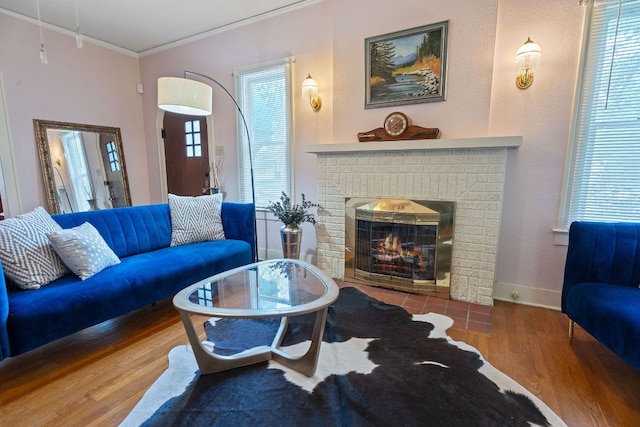 living area featuring crown molding, baseboards, a brick fireplace, and wood finished floors