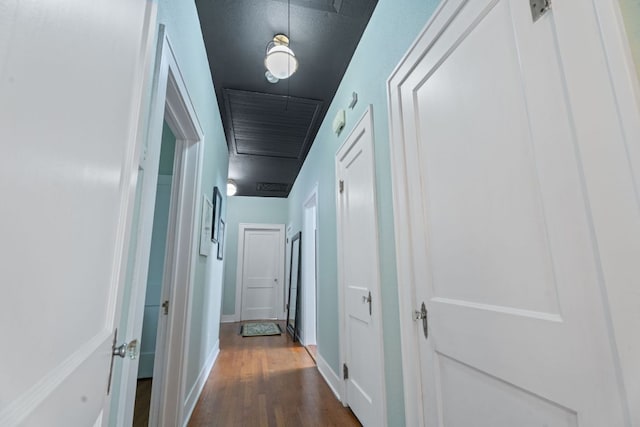 corridor featuring baseboards, attic access, and dark wood-type flooring