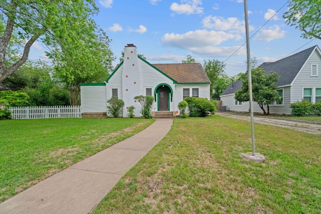 bungalow-style home featuring fence, a chimney, a shingled roof, and a front yard