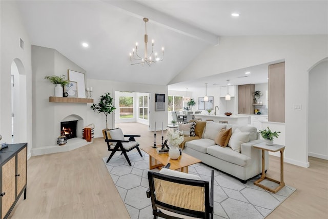 living area featuring arched walkways, a warm lit fireplace, light wood-style flooring, and visible vents