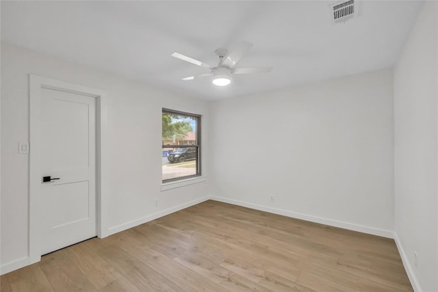 spare room featuring visible vents, a ceiling fan, light wood-style floors, and baseboards