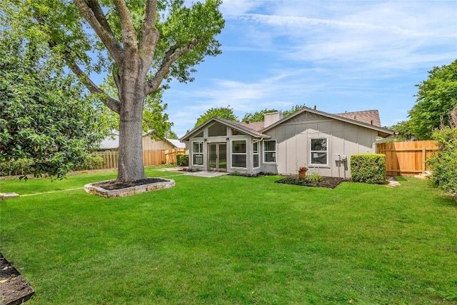 back of property with board and batten siding, a lawn, fence, and a chimney