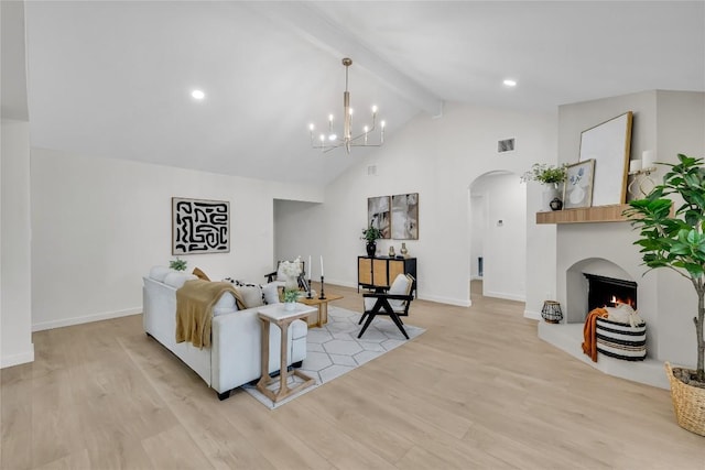 living area featuring beam ceiling, visible vents, arched walkways, light wood-style flooring, and a lit fireplace