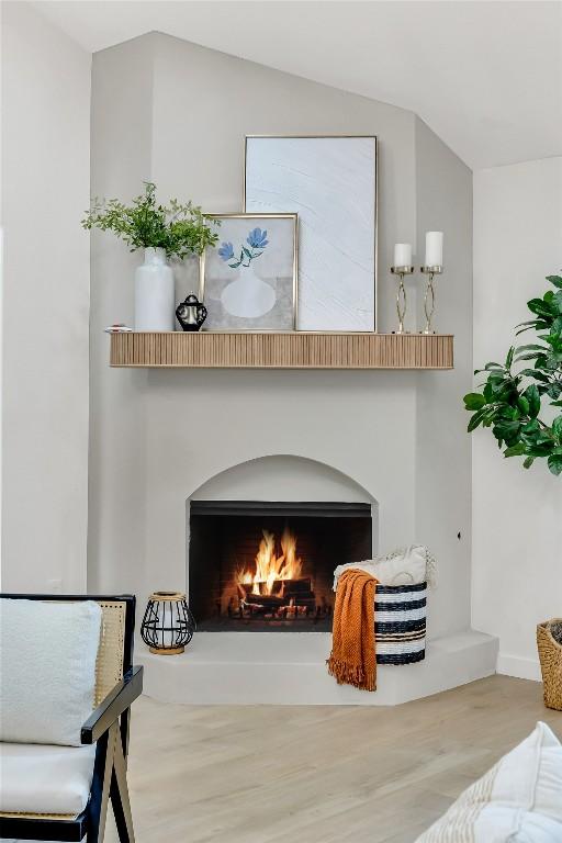 room details featuring a warm lit fireplace and wood finished floors