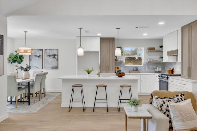 kitchen with open shelves, light countertops, gas range, tasteful backsplash, and visible vents