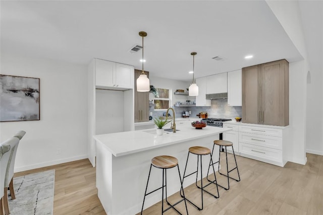 kitchen with visible vents, tasteful backsplash, open shelves, light wood-type flooring, and a sink