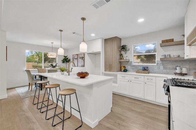 kitchen with black gas stove, open shelves, visible vents, and a wealth of natural light