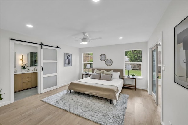 bedroom featuring recessed lighting, light wood-type flooring, and a barn door