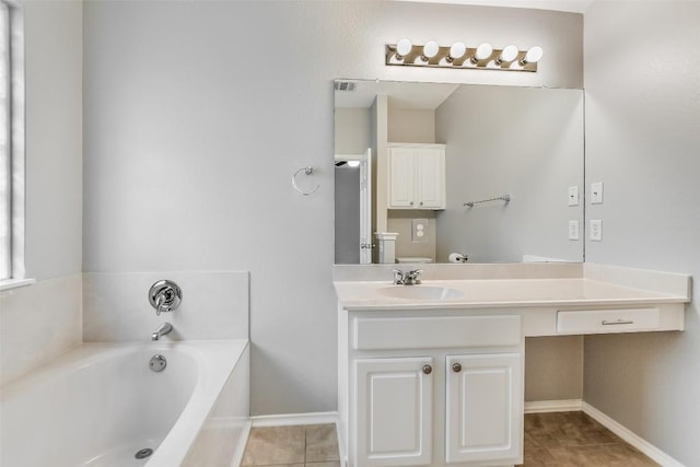 bathroom featuring tile patterned floors, baseboards, vanity, and a bath