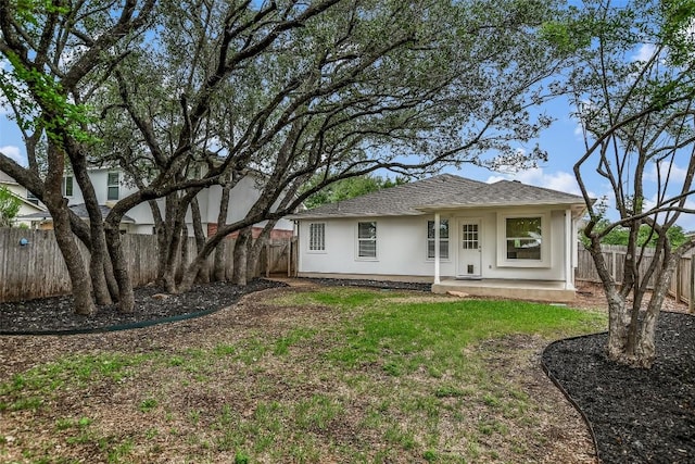 back of house featuring a fenced backyard, roof with shingles, and stucco siding