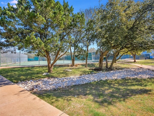 view of yard with fence and a tennis court