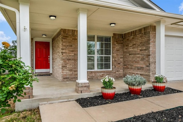 view of exterior entry featuring a porch and brick siding