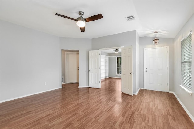 unfurnished room featuring baseboards, a ceiling fan, wood finished floors, and visible vents