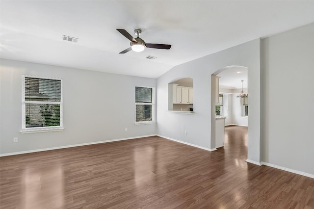 unfurnished living room with dark wood-style flooring, arched walkways, a ceiling fan, vaulted ceiling, and visible vents