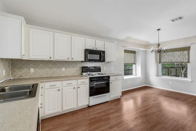 kitchen with visible vents, range with gas stovetop, an inviting chandelier, black microwave, and a sink