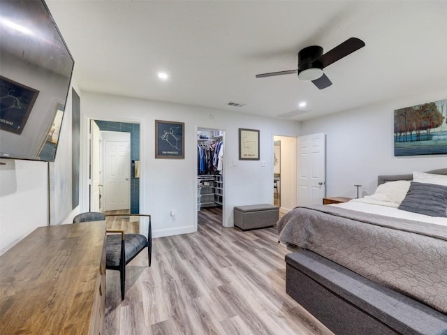 bedroom featuring light wood-style floors, a walk in closet, recessed lighting, a ceiling fan, and baseboards