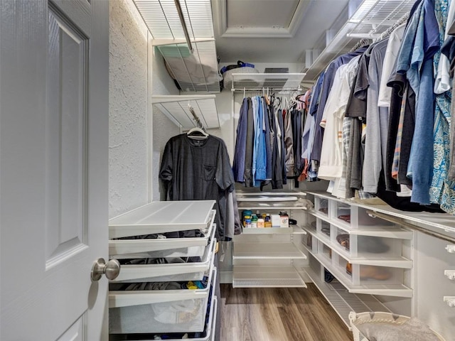 walk in closet with wood finished floors and attic access