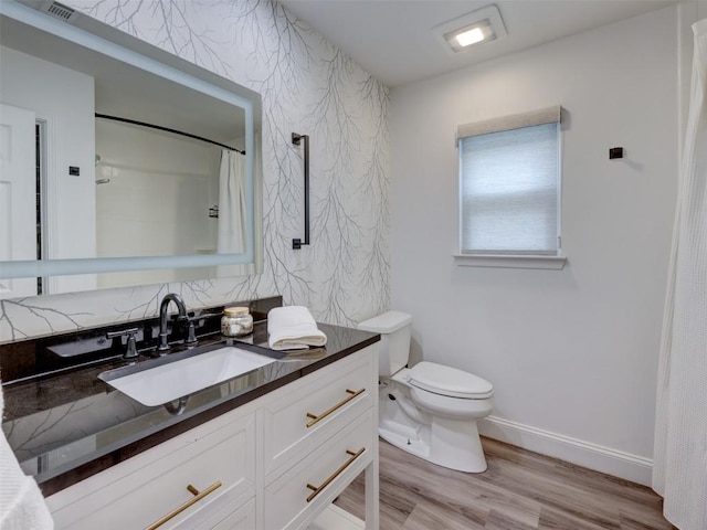 bathroom with toilet, wood finished floors, baseboards, and vanity