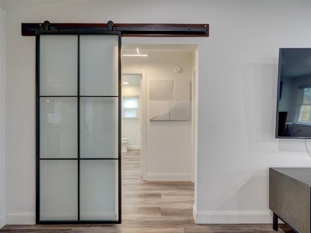 bathroom featuring baseboards, wood finished floors, and toilet