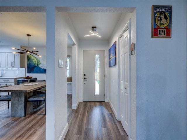 foyer featuring wood finished floors, baseboards, and a chandelier