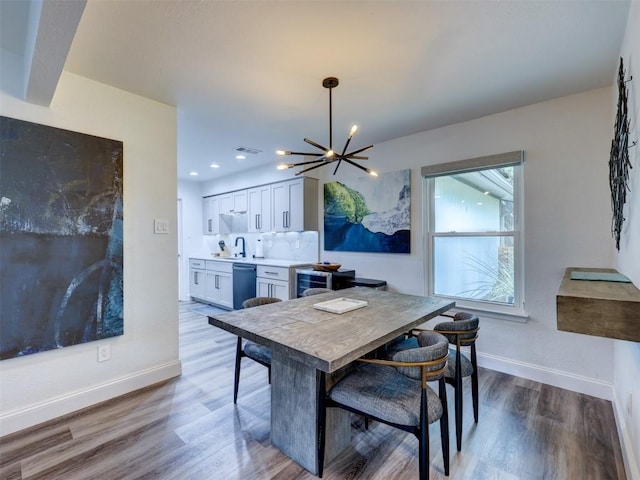 dining space featuring a chandelier, wood finished floors, baseboards, and recessed lighting