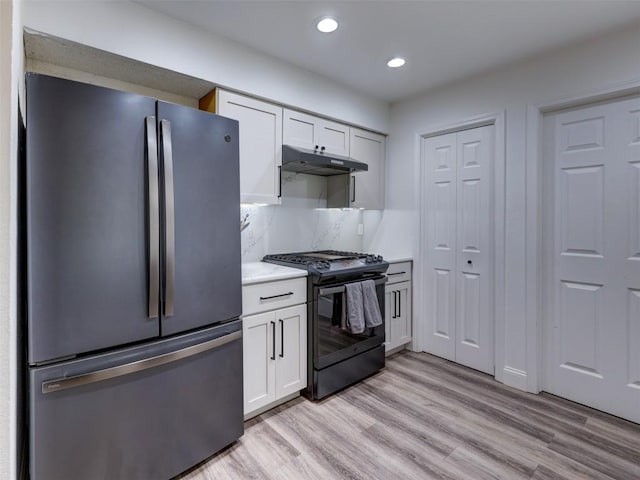kitchen with black range with gas cooktop, freestanding refrigerator, under cabinet range hood, recessed lighting, and light wood-type flooring